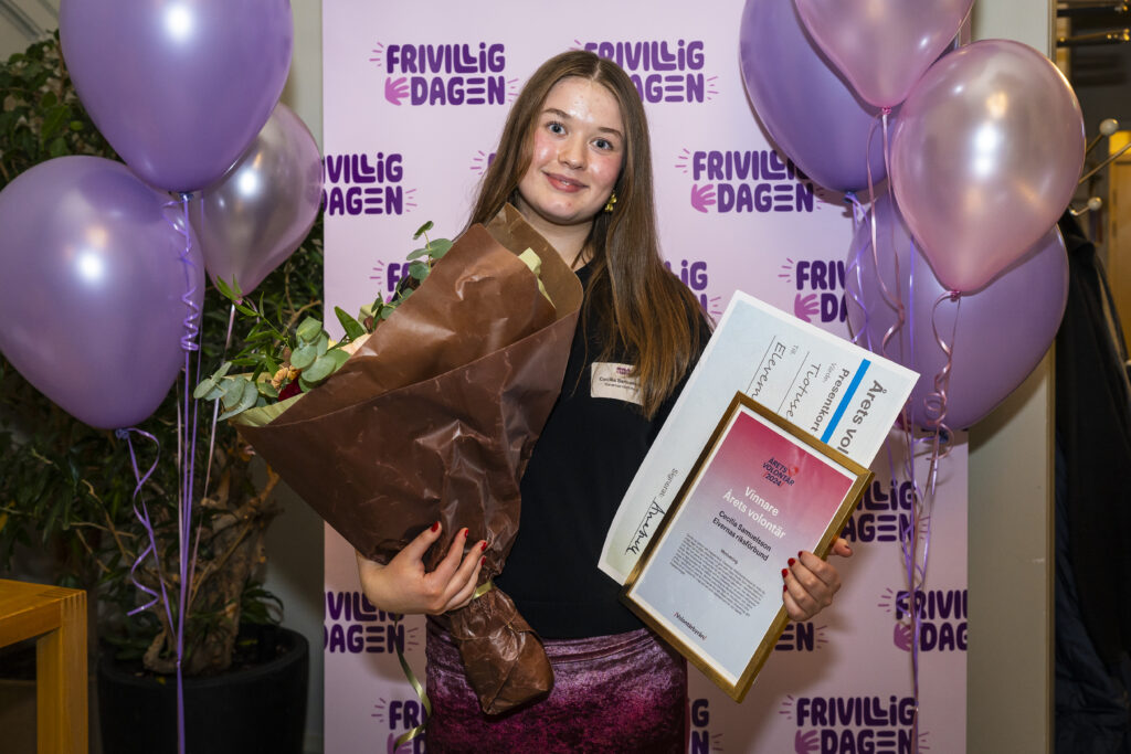 Vinnare av Årets volontär 2024 håller i diplom och blommor